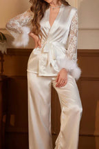 Woman wearing a white satin robe and pant set with lace sleeves and feather trim