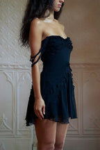 Side view of a woman wearing a black off-the-shoulder dress with ruffled details