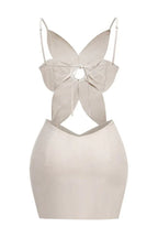 Back view of a beige linen blend dress with a flower-shaped bodice, cut-out detail, and back tie closure.