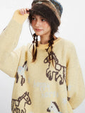 Detail view of the horse graphic print on the yellow knit sweater.