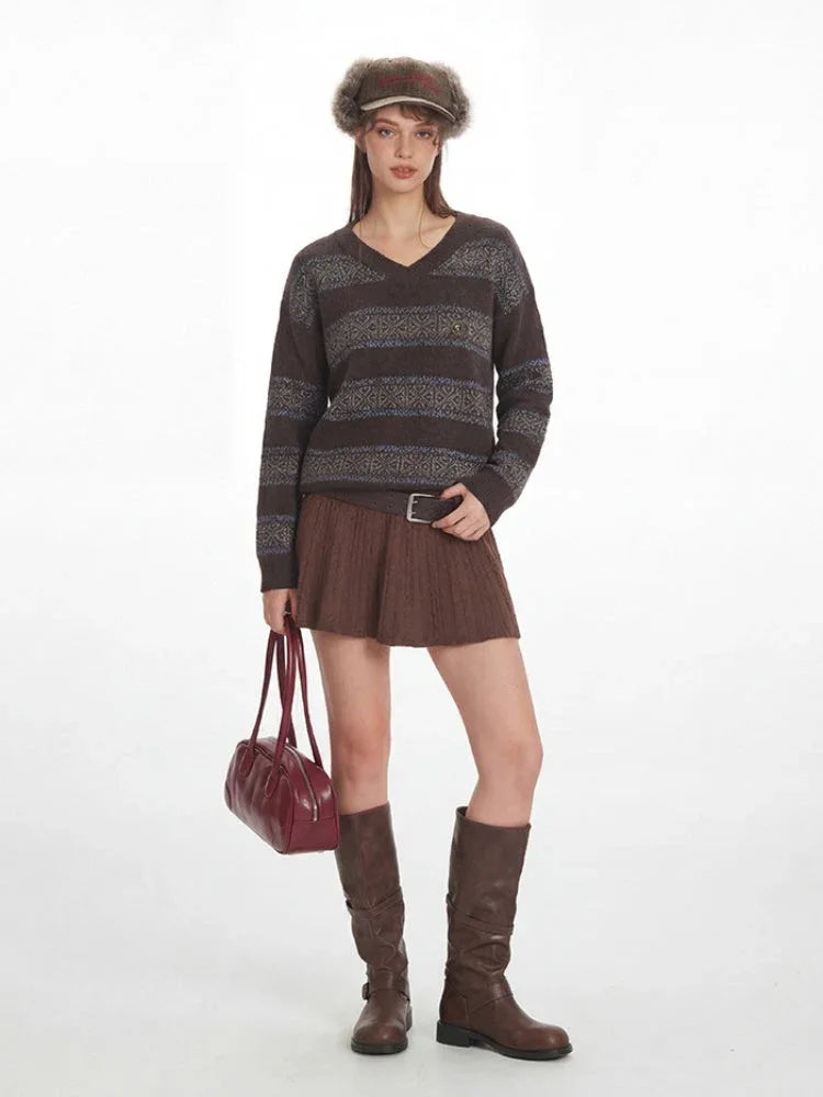 Front view of a woman in a brown V-neck knit sweater with horizontal stripes and a patterned yoke.