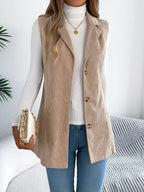 Woman wearing a beige corduroy longline vest over a white turtleneck and blue jeans.