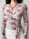 Front view of a woman in a fitted floral wrap top with a tie at the waist.