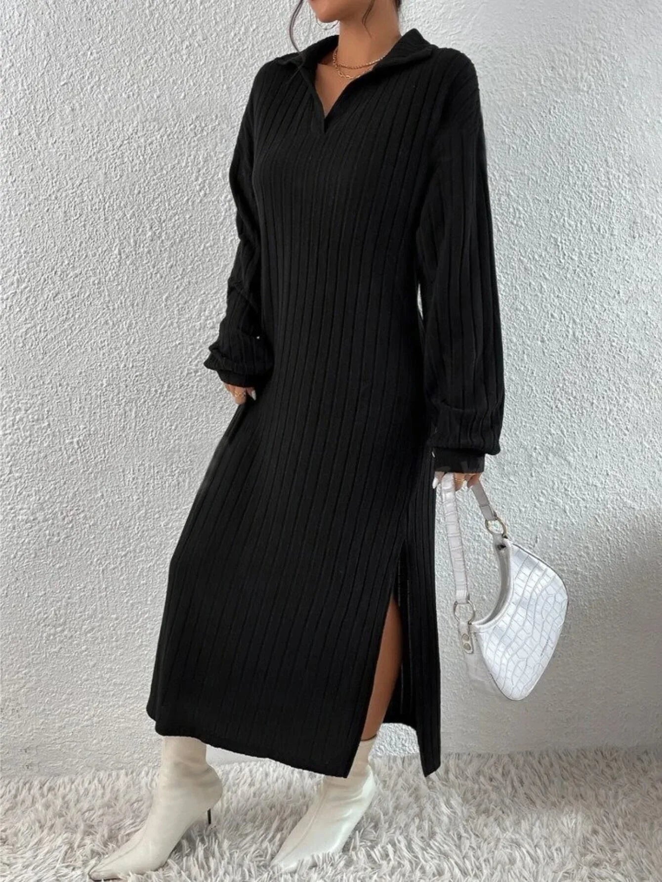 Side profile of a model wearing a black ribbed knit midi dress with a high slit.