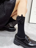 view of black knee-high socks with a floral accent, paired with a dark skirt and loafers