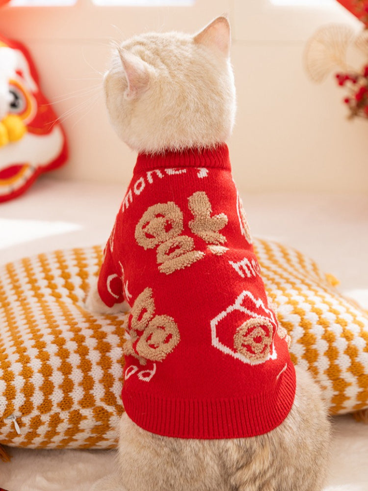 White cat wearing a red knit sweater with beige lucky fortune pattern