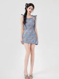 Woman posing in a short blue plaid dress with adjustable shoulder ties