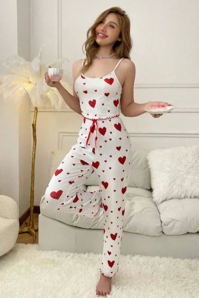 Woman wearing white ribbed knit pajamas with red heart print, featuring spaghetti straps and wide-leg pants. Main image