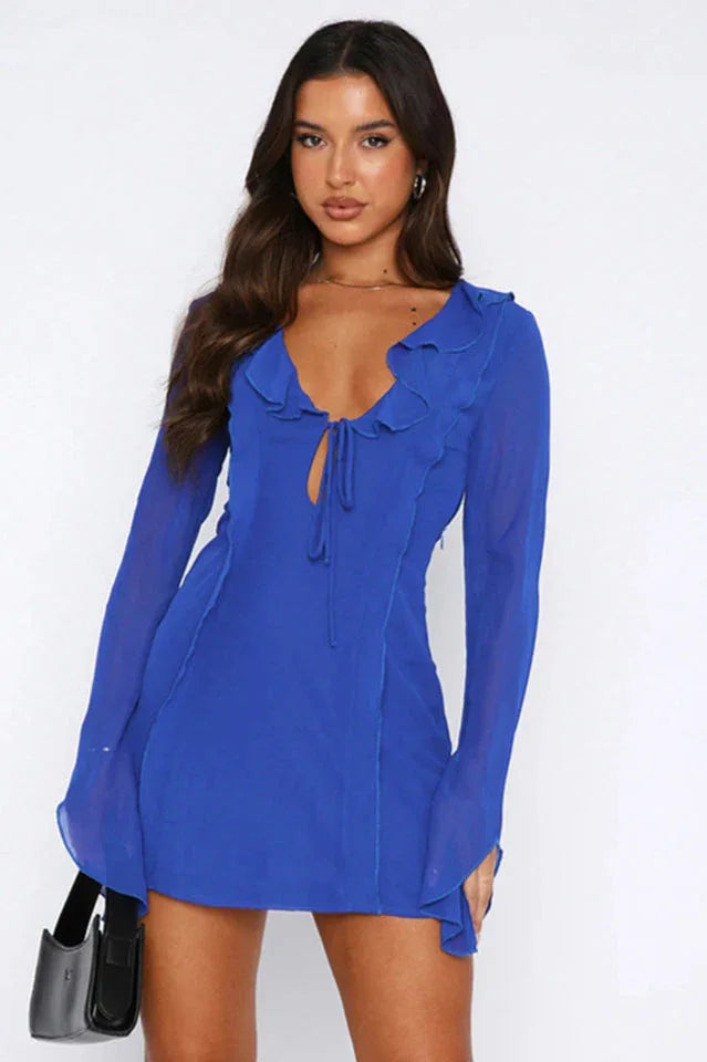 Side view of a woman in a royal blue sheer chiffon mini dress with long bell sleeves.