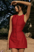 Woman posing in a red sleeveless dress with her arm raised