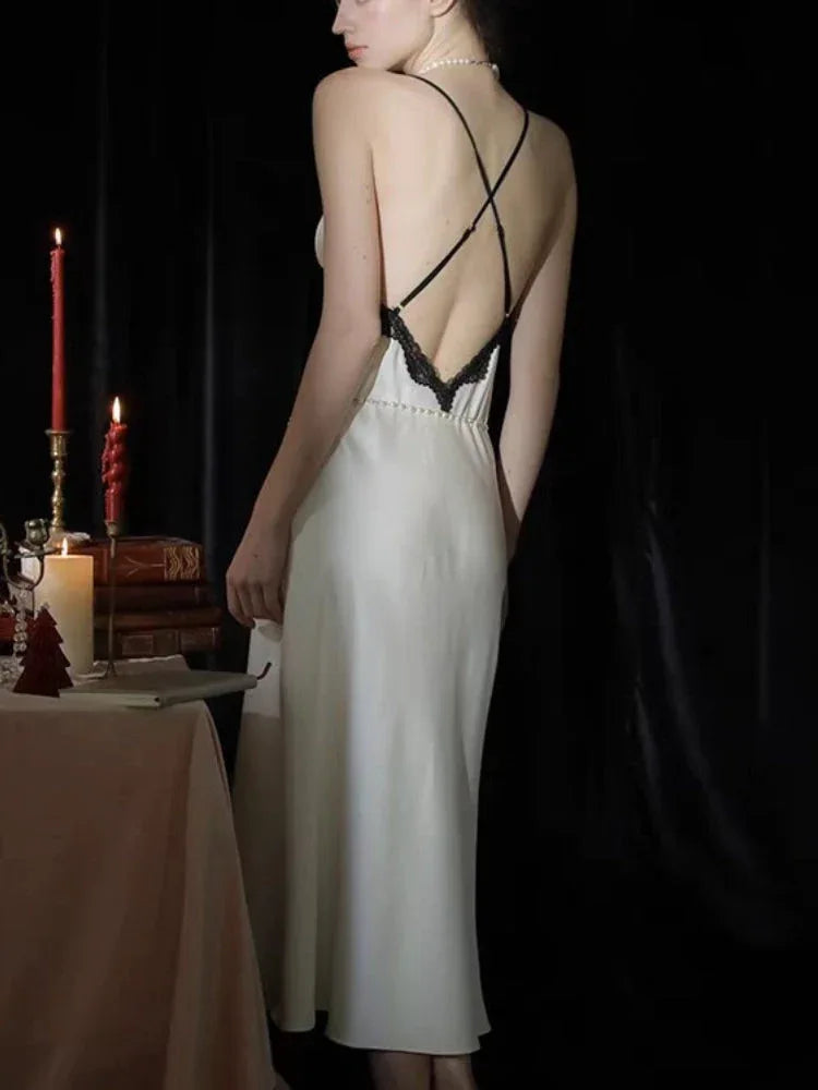 Back view of a woman in a white satin slip dress with criss-cross spaghetti straps and lace detail