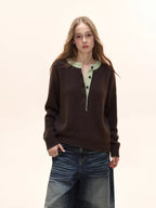Woman wearing a brown long-sleeved knit sweater with a light green contrast neckline and button-up placket, paired with distressed denim jeans.