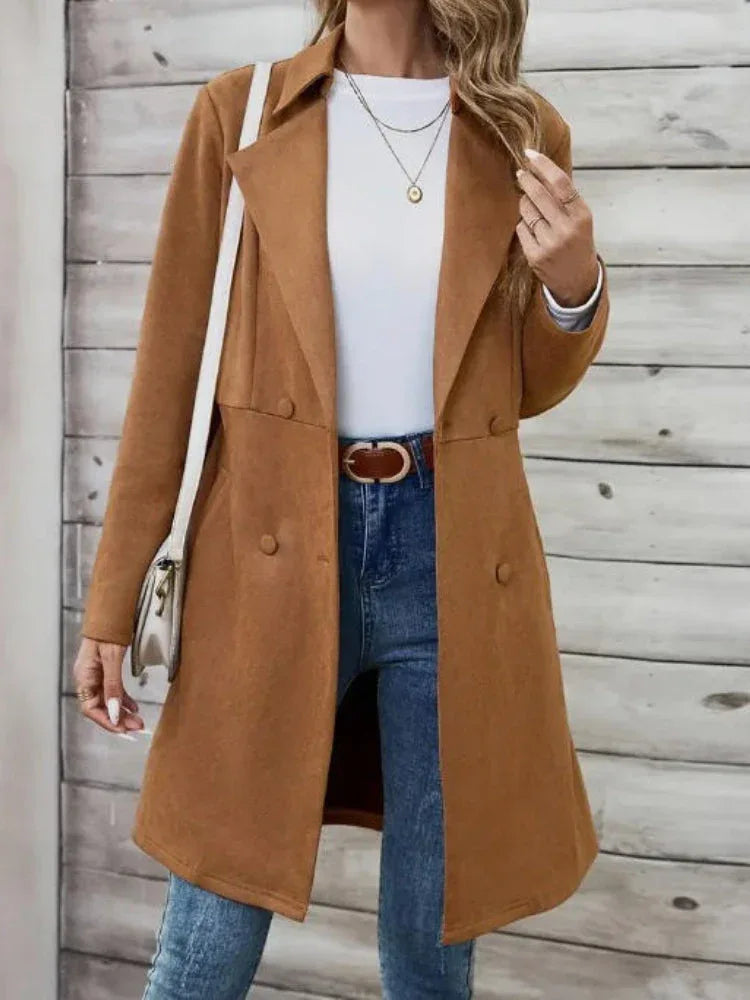 Woman wearing a brown suede-like coat with a white top, blue jeans, and accessories.