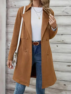 Woman wearing a brown suede-like coat with a white top, blue jeans, and accessories.