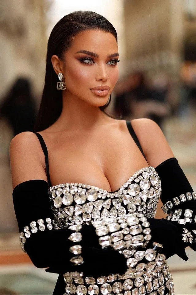 Close-up of a woman's face and upper body, showcasing the intricate crystal embellishments on her strapless mini dress and gloves.