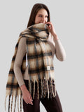Close-up of a woman in a cream coat and a plaid scarf with fringe detail