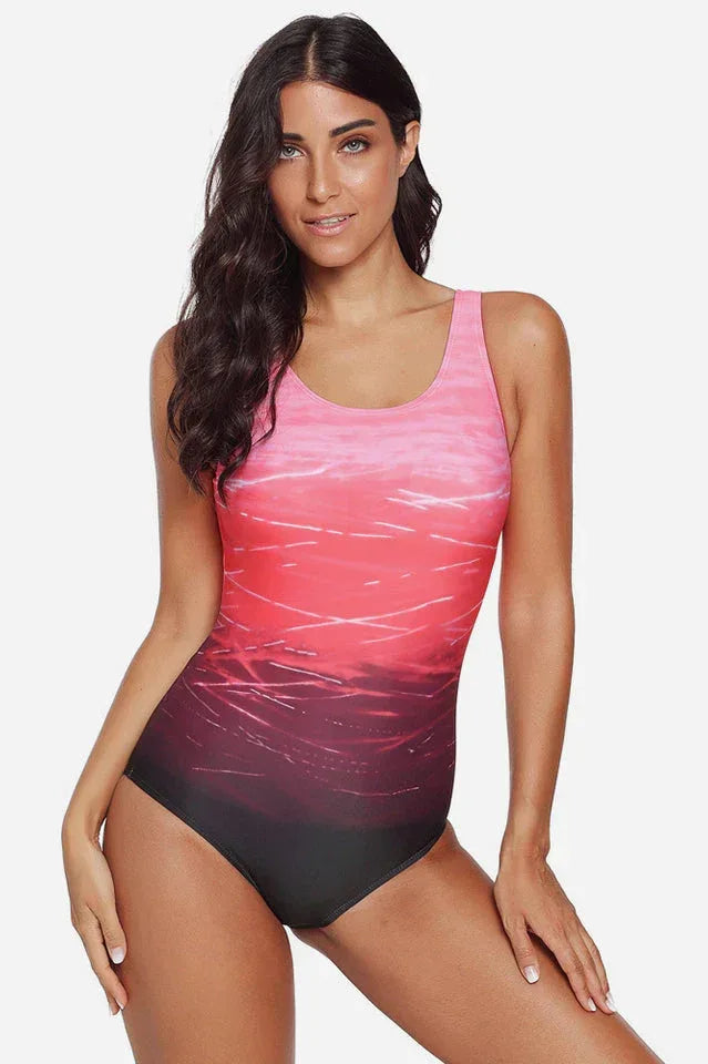 Woman in a pink and red ombre one-piece swimsuit from the front.
