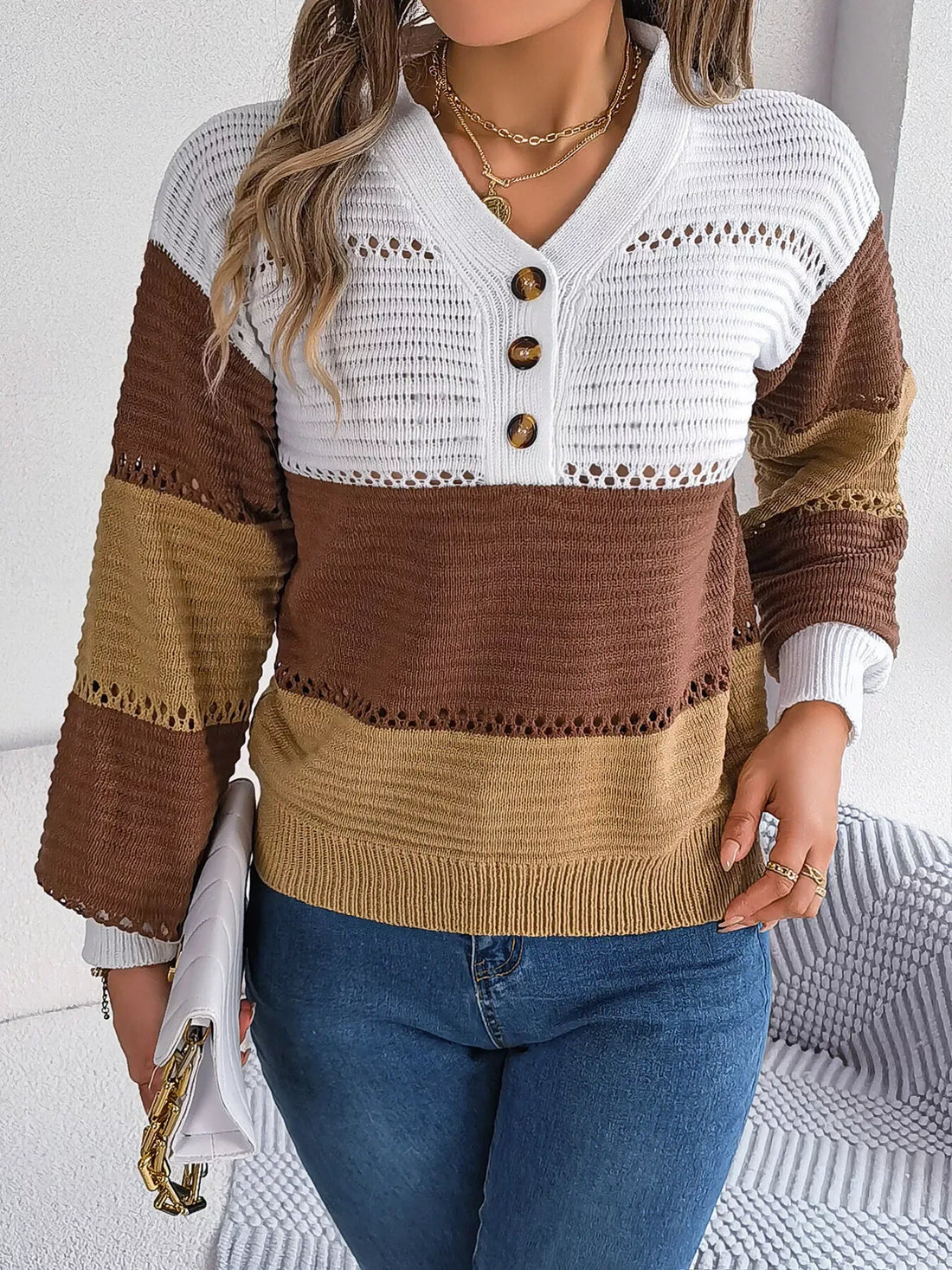 Woman wearing a brown, tan, and white color block knit sweater with a V-neck and button placket.