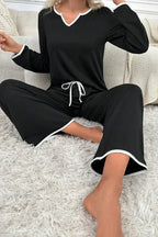 Close-up of woman's legs in black pajama pants with white piping detail.