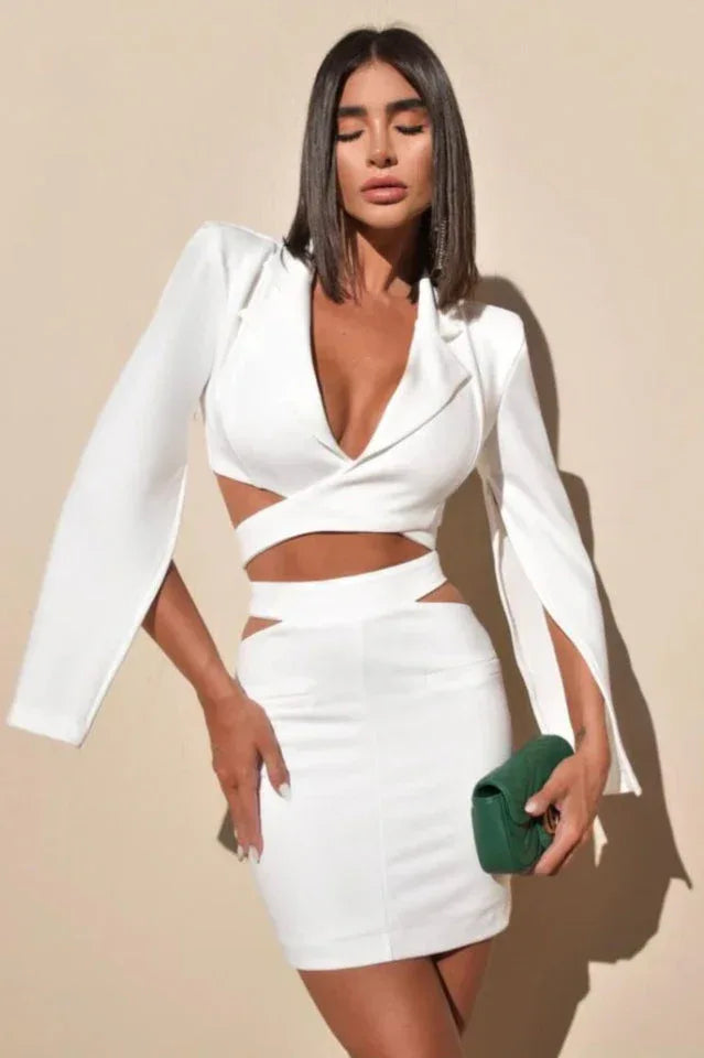 Woman wearing a white long-sleeve crop top with cut-out details and a matching white mini skirt. Main image