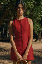 Woman wearing a red sleeveless button-front dress outdoors