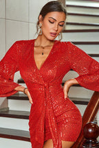 Close-up of a woman's face and upper body in a red sequined wrap dress.