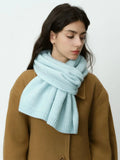 Woman in a camel coat and light blue scarf
