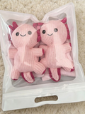 Two pink knit crew socks with axolotl appliques packaged together in a clear bag