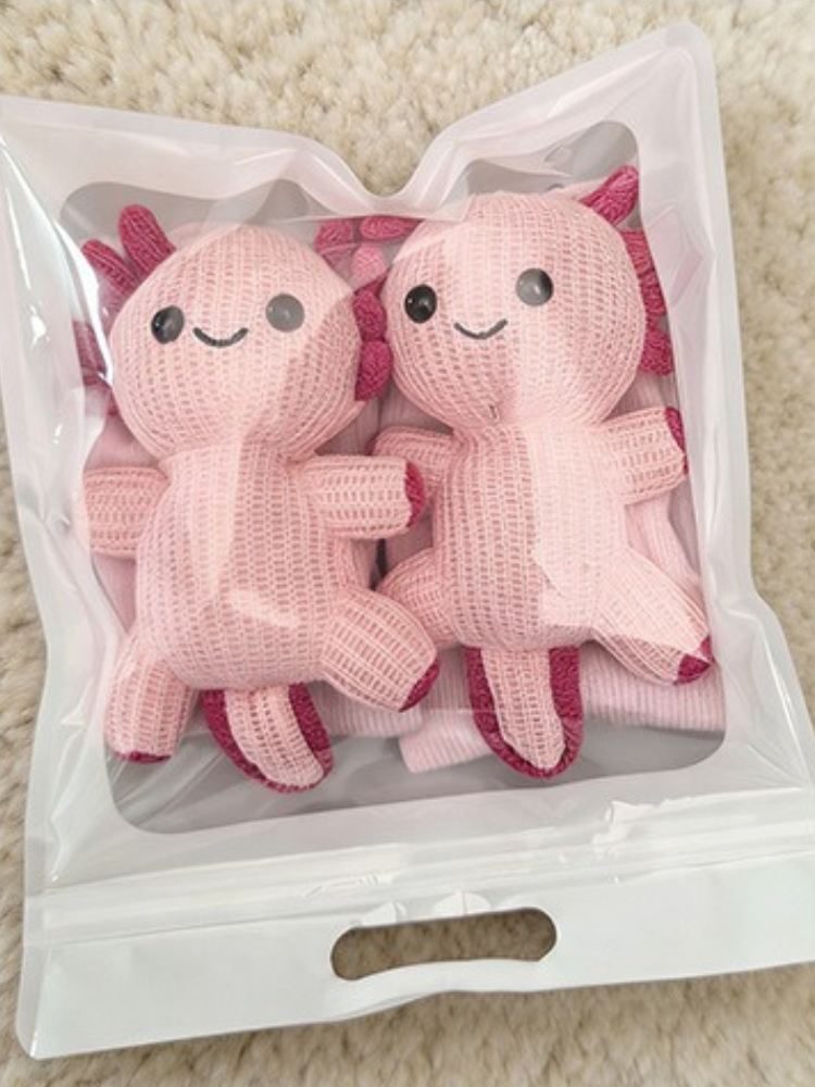Two pink knit crew socks with axolotl appliques packaged together in a clear bag