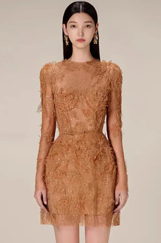 Woman wearing a short, long-sleeved, high-neck dress in a tan lace fabric with sequin embellishments. Main image
