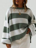Woman wearing a green and white striped oversized knit sweater with crew neck and long cuffed sleeves.