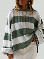 Woman wearing a green and white striped oversized knit sweater with crew neck and long cuffed sleeves.