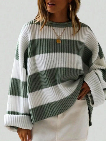 Woman wearing a green and white striped oversized knit sweater with crew neck and long cuffed sleeves.