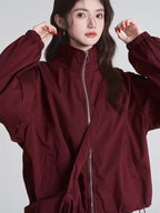 Woman wearing a maroon bomber jacket with a high collar and full zip front