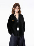 Close-up of the woman's upper body, showcasing the details of the black knit cardigan, including the V-neckline, button-down closure, and the embroidered dachshund graphic.