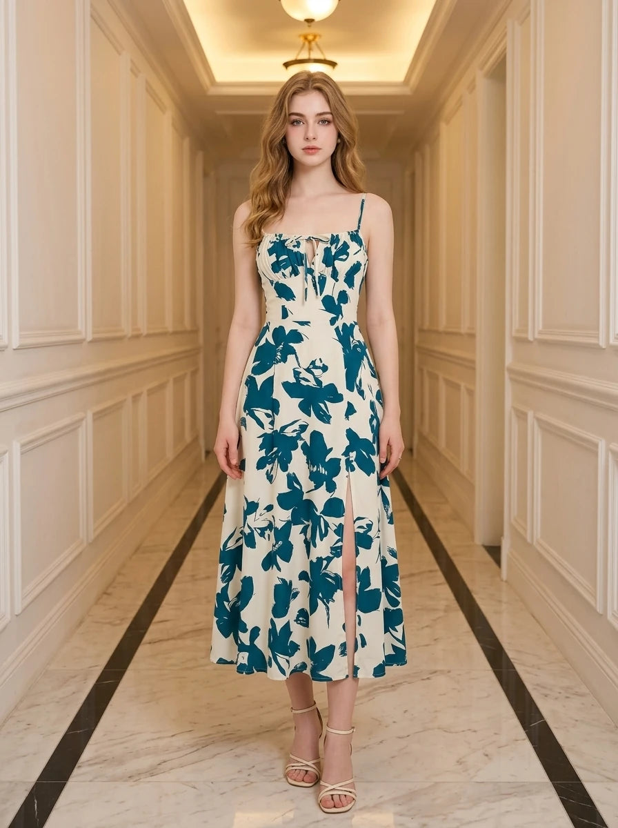 Woman wearing a cream and teal floral print midi dress with spaghetti straps and a tie-front bodice, standing in a hallway.