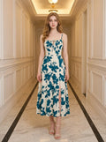 Woman wearing a cream and teal floral print midi dress with spaghetti straps and a tie-front bodice, standing in a hallway.