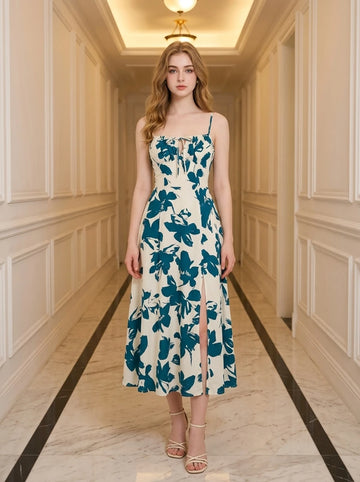 Woman wearing a cream and teal floral print midi dress with spaghetti straps and a tie-front bodice, standing in a hallway.