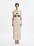 Woman wearing a cream knit maxi dress with black striped bodice and spaghetti straps, front view