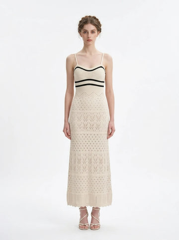 Woman wearing a cream knit maxi dress with black striped bodice and spaghetti straps, front view