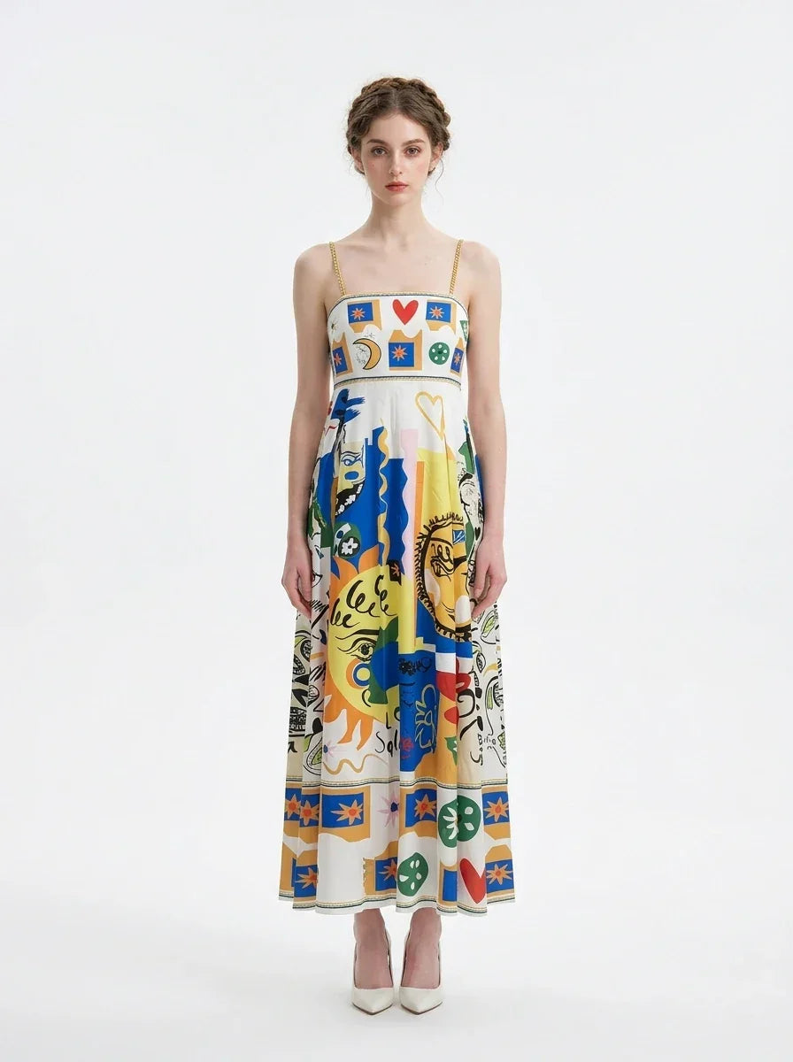 Woman wearing a white midi dress with a colorful abstract graphic print and gold chain spaghetti straps.
