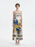 Woman wearing a white midi dress with a colorful abstract graphic print and gold chain spaghetti straps.