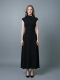 Woman wearing a sleeveless black A-line midi dress with a mock neck.