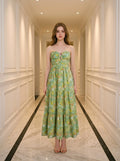 Woman wearing a green floral print strapless maxi dress standing in a hallway.