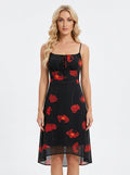 Woman wearing a black midi dress with a red floral print, spaghetti straps, and a tie-front bodice