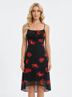 Woman wearing a black midi dress with a red floral print, spaghetti straps, and a tie-front bodice