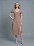 Woman wearing a brown midi dress with a white abstract print, puff sleeves, sweetheart neckline, and a high side slit.