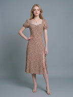 Woman wearing a brown midi dress with a white abstract print, puff sleeves, sweetheart neckline, and a high side slit.