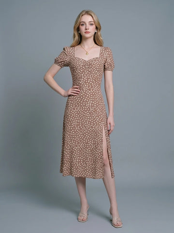 Woman wearing a brown midi dress with a white abstract print, puff sleeves, sweetheart neckline, and a high side slit.