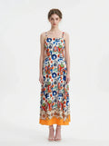 Woman wearing a vibrant printed midi dress with spaghetti straps and a square neckline.